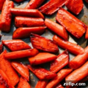 Brown Sugar Glazed Roasted Carrots 2 Close-up of golden brown sugar roasted carrots on a serving plate, garnished with fresh herbs.