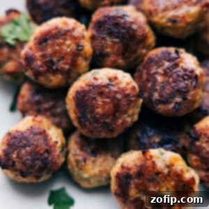 Irresistible Chicken Meatballs 3 Close-up of baked chicken meatballs, perfectly golden brown and garnished with fresh herbs.