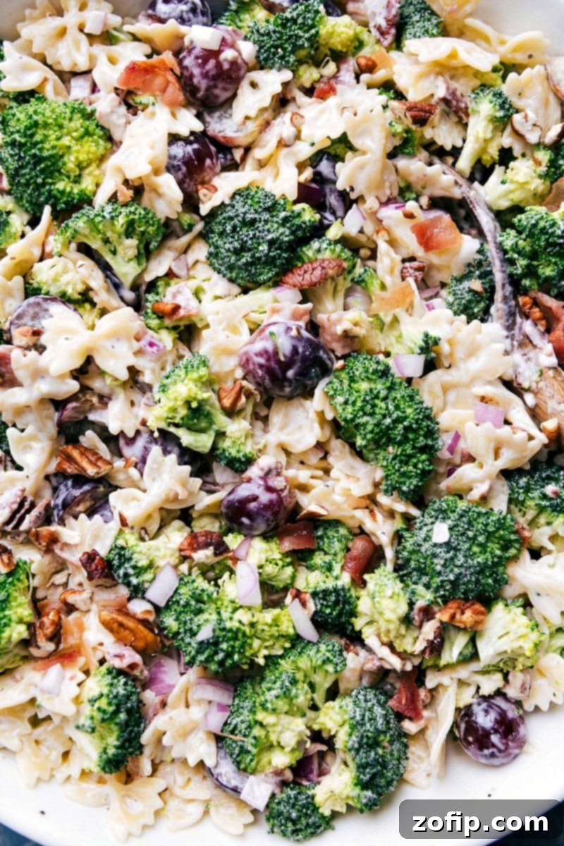 Delicious Broccoli Grape Pasta Salad in a Bowl with Serving Spoon Delicious and healthy side dish, Broccoli Grape Pasta Salad, served in a pristine white bowl with a silver serving spoon, artfully arranged and ready to be enjoyed at a summer gathering or potluck.