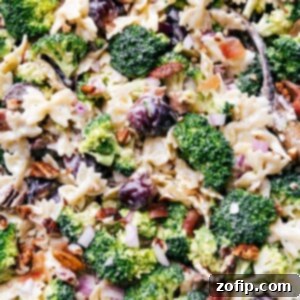 Sweet and Savory Pasta Salad 3 Delicious and healthy side dish, Broccoli Grape Pasta Salad, in a white bowl with a serving spoon, ready to be enjoyed at a summer gathering.