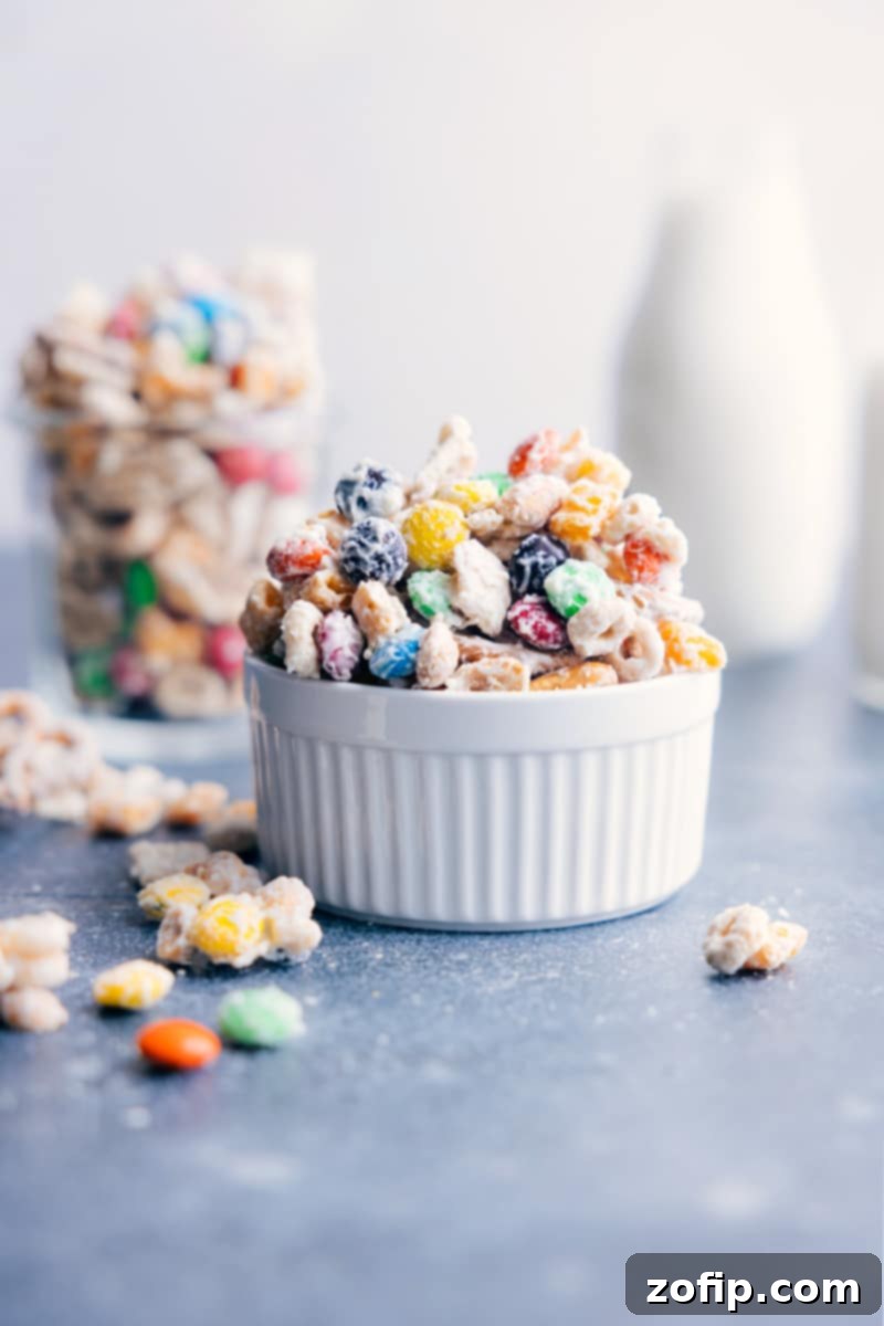 The Ultimate White Chocolate Chex Mix: Crispy Cereal, Pretzels, Peanuts, M&M's, Coated in White Chocolate. Recipe via ChelseasMessyApron #dessert #best #quick #easy #simple #m&ms #familyfriendly #kidfriendly #pretzels #cereal #whitechocolate #snackmix A beautiful bowl of homemade White Chocolate Chex Mix, featuring crispy cereals, mini pretzels, roasted peanuts, and colorful M&M's coated in creamy white chocolate, ready to be enjoyed.