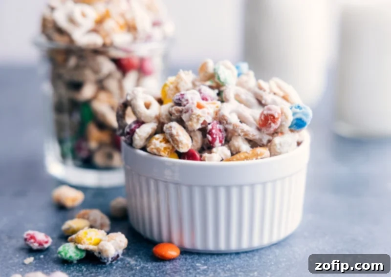 Delicious White Chocolate Chex Mix Ready to Serve: Cereal, Pretzels, Peanuts, M&M's, All Coated in White Chocolate. Recipe via ChelseasMessyApron #dessert #best #quick #easy #simple #m&ms #familyfriendly #kidfriendly #pretzels #cereal #whitechocolate #snackmix A large, inviting bowl filled with the finished White Chocolate Chex Mix, ready to be served and enjoyed, showcasing its irresistible appeal.