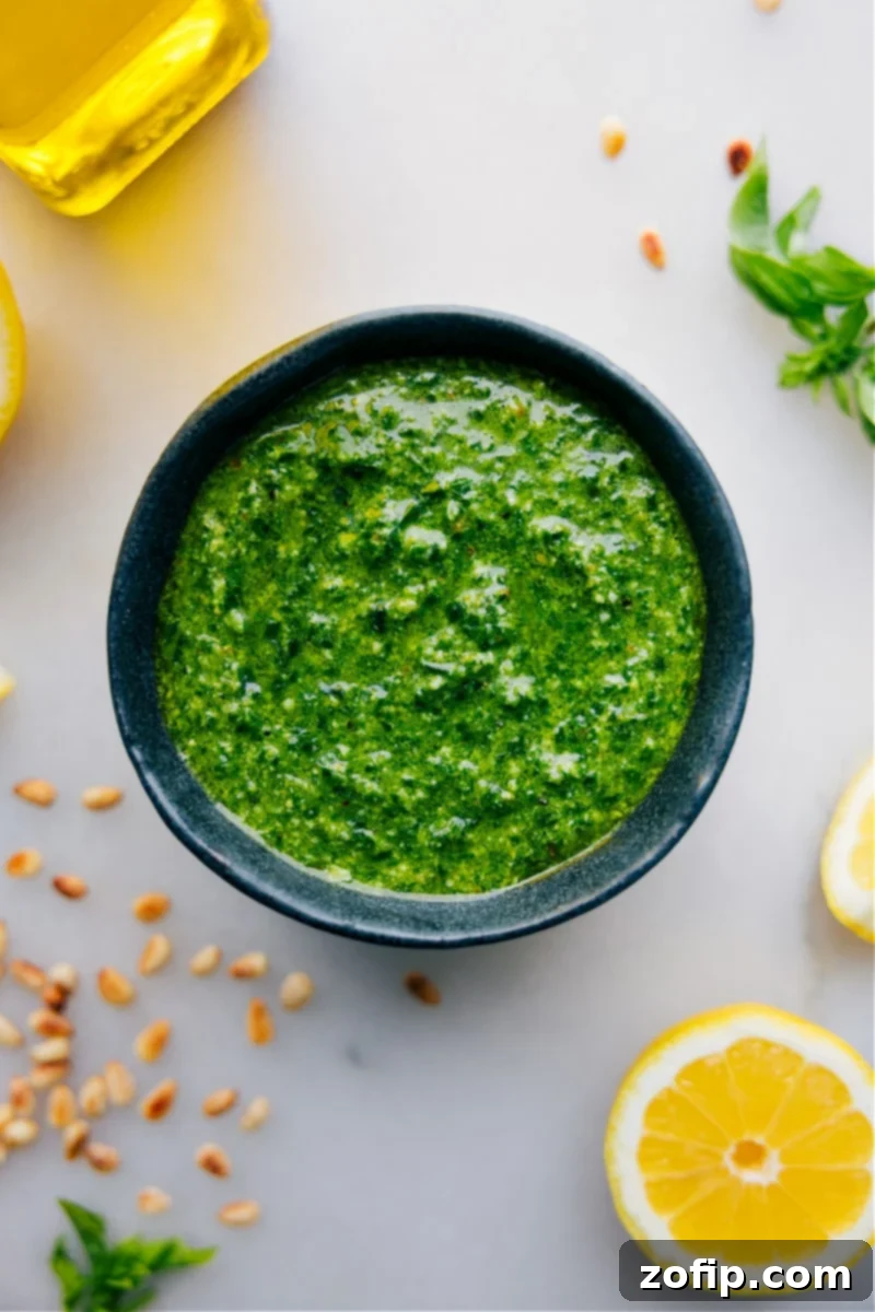 Overhead image of freshly made Pesto sauce in a bowl, garnished with basil leaves and pine nuts, ready to be served or used in a dish.