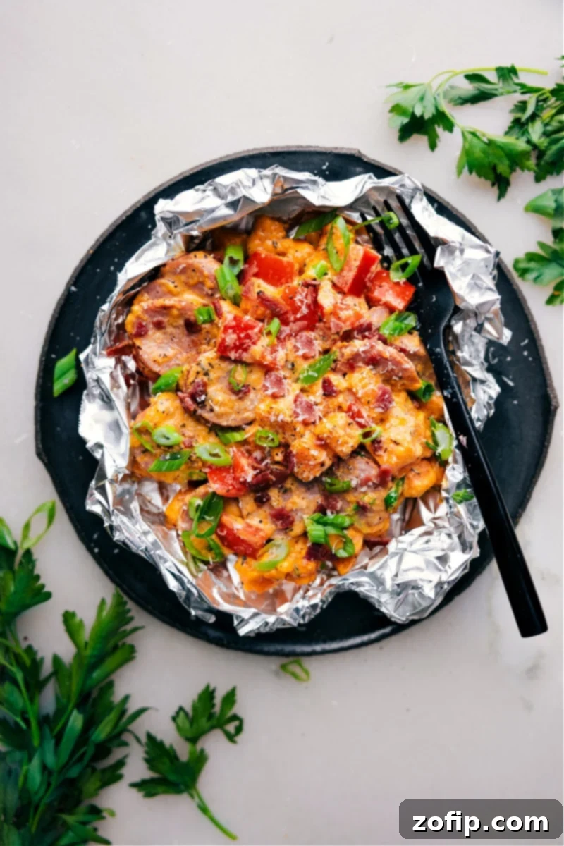 Overhead image of Creamy Sweet Potato and Sausage in a foil packet, garnished with fresh herbs, showcasing the tender sweet potatoes, smoky sausage, and creamy sauce.