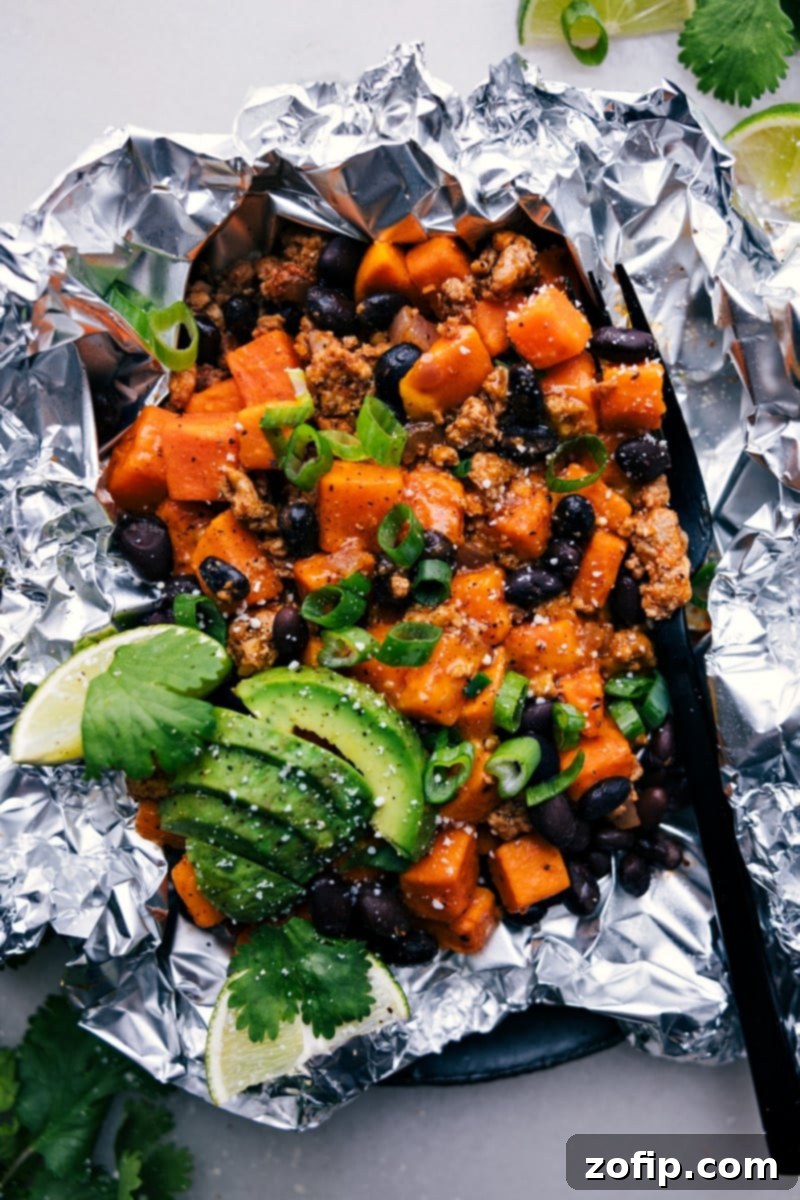 Taco Sweet Potato Foil Packets fresh off the grill, showcasing the vibrant ingredients and cheesy topping.