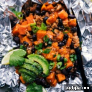 A close-up shot of an opened Taco Sweet Potato Foil Packet, showing the rich filling of taco meat, sweet potatoes, and melted cheese, garnished with fresh cilantro.