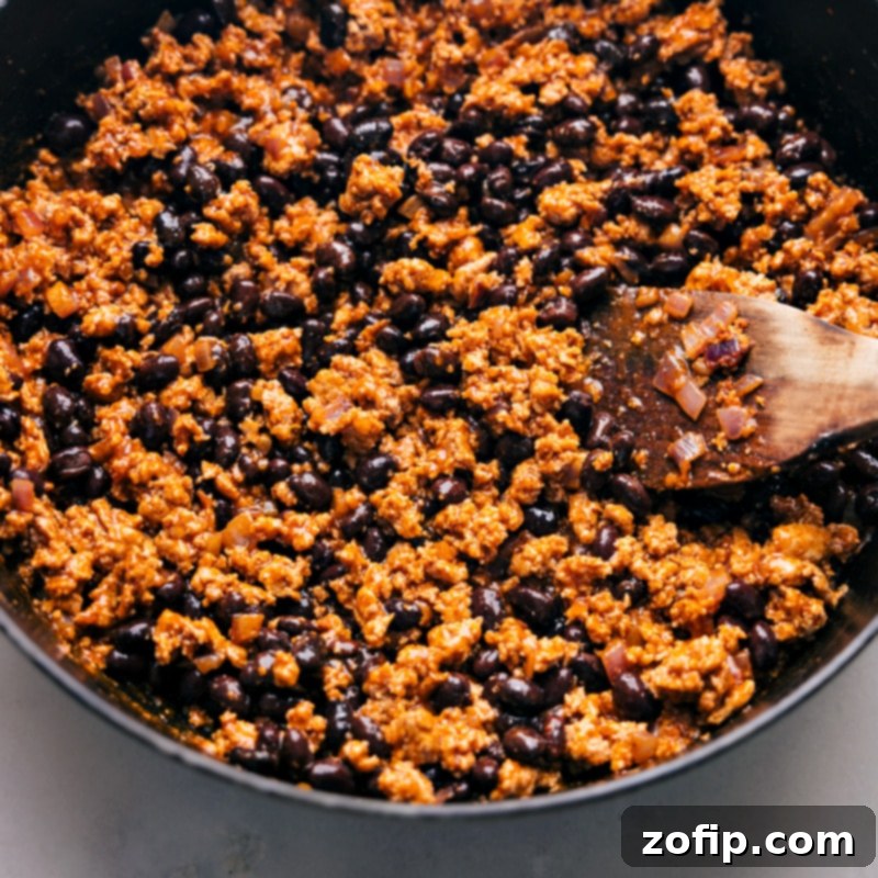 Process shot of Taco Sweet Potato Foil Packets showing all the cooked taco meat and par-boiled sweet potatoes mixed together in a large pot, ready for assembly into foil packets.
