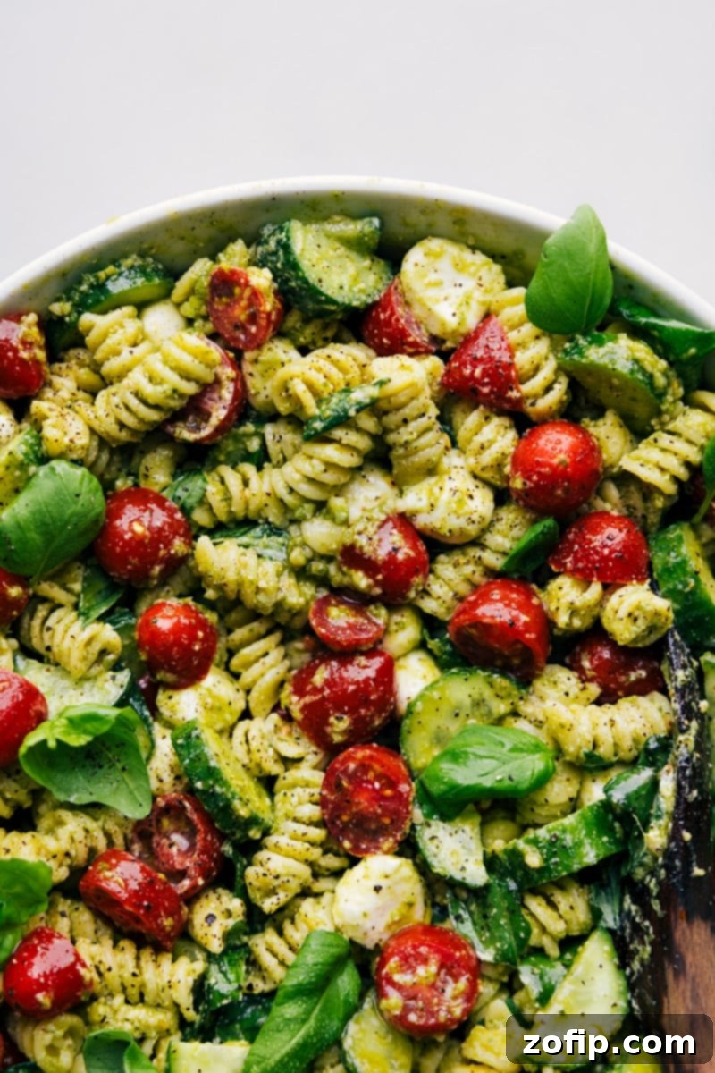 Up-close overhead image of the ready-to-eat Pesto Pasta Salad, garnished beautifully with fresh basil leaves, suggesting it's ready to be served and enjoyed.