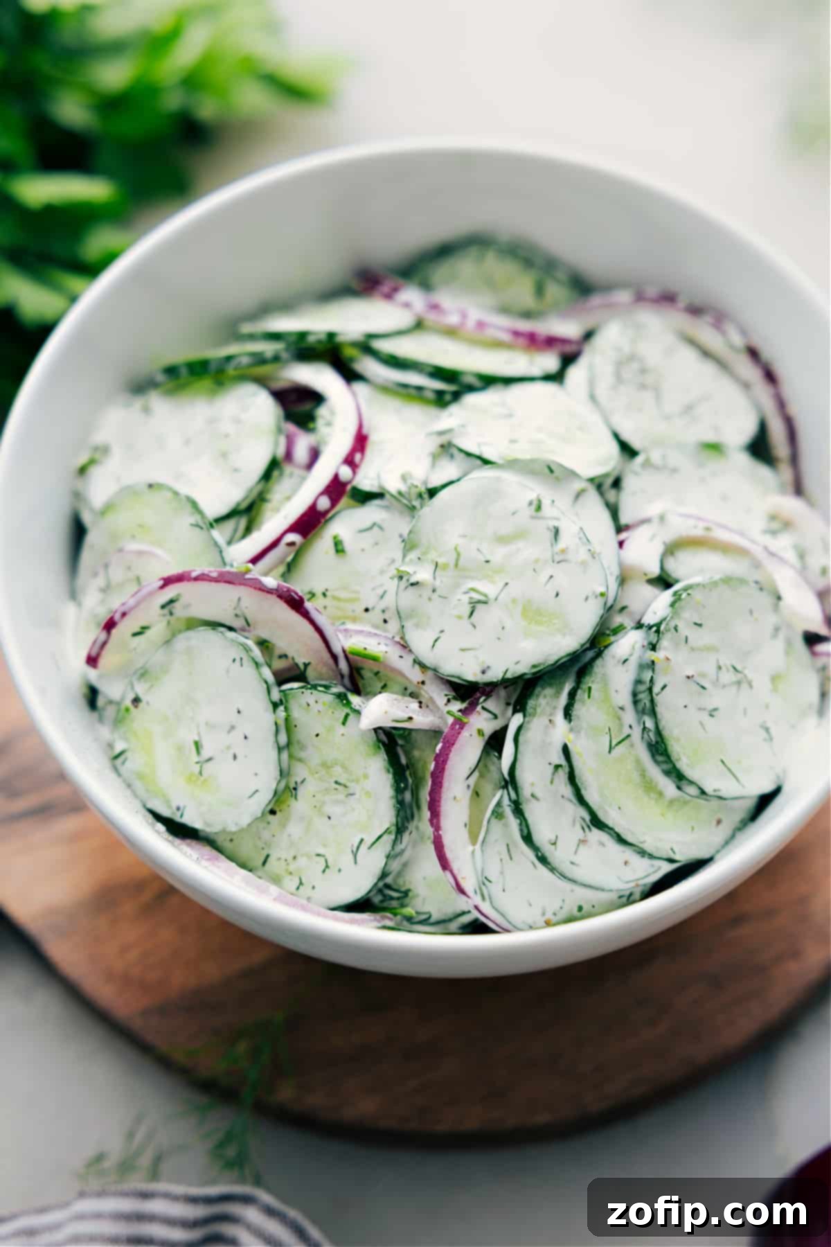 A beautifully presented bowl of creamy cucumber salad, garnished and ready to be served and enjoyed.