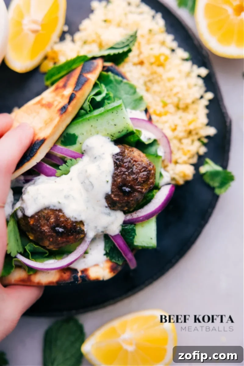 These Beef Kofta Meatballs are packed with a bold blend of Middle Eastern spices that result in a robust and flavorful profile. These meatballs have a nice tender interior with a beautiful charred exterior. Serve them in a charred pita, accompanied by the best mint-yogurt sauce and fresh, crunchy veggies! Recipe via chelseasmessyapron #dinner #quick #easy #simple #familyfriendly #kidfriendly #beef #kofta #meatballs Overhead image of the Beef Kofta Meatballs served in pita bread with mint yogurt sauce and fresh vegetables