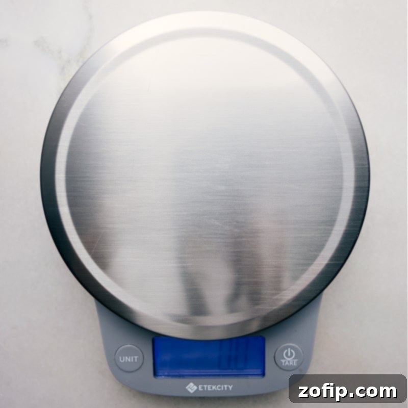 Close-up view of a digital food scale displaying a precise measurement, highlighting the importance of weight-based measuring in baking