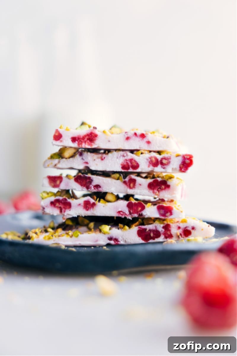 A perfectly frozen piece of raspberry yogurt bark with toppings, ready to be enjoyed as a healthy snack.