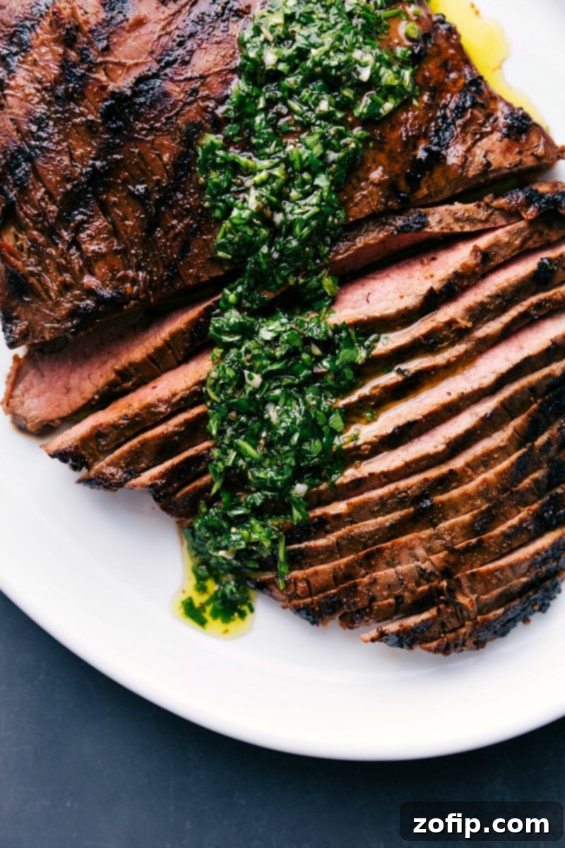 Perfectly Grilled Flank Steak 4 Sliced grilled flank steak topped with flavorful chimichurri sauce, presented beautifully on a platter.