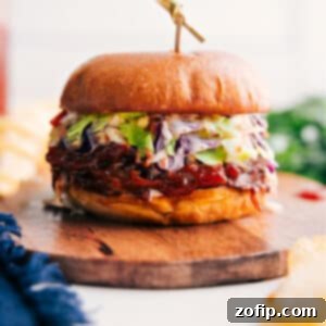 Slow Cooked Pulled Pork Sandwich Perfection 3 A top-down view of a delectable pulled pork sandwich with crispy coleslaw, served on a plate with a side of extra BBQ sauce. The golden bun holds the juicy pork and fresh slaw beautifully.