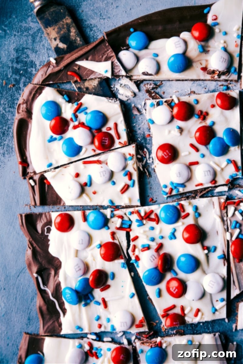 Overhead image of a beautifully arranged Fourth of July Bark with red, white, and blue M&M's and star sprinkles on a white background, highlighting its festive appeal for Independence Day celebrations.