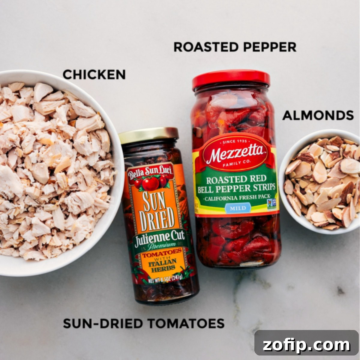 All the fresh ingredients for the pesto chicken salad laid out meticulously on a table, perfectly prepped and ready for mixing.