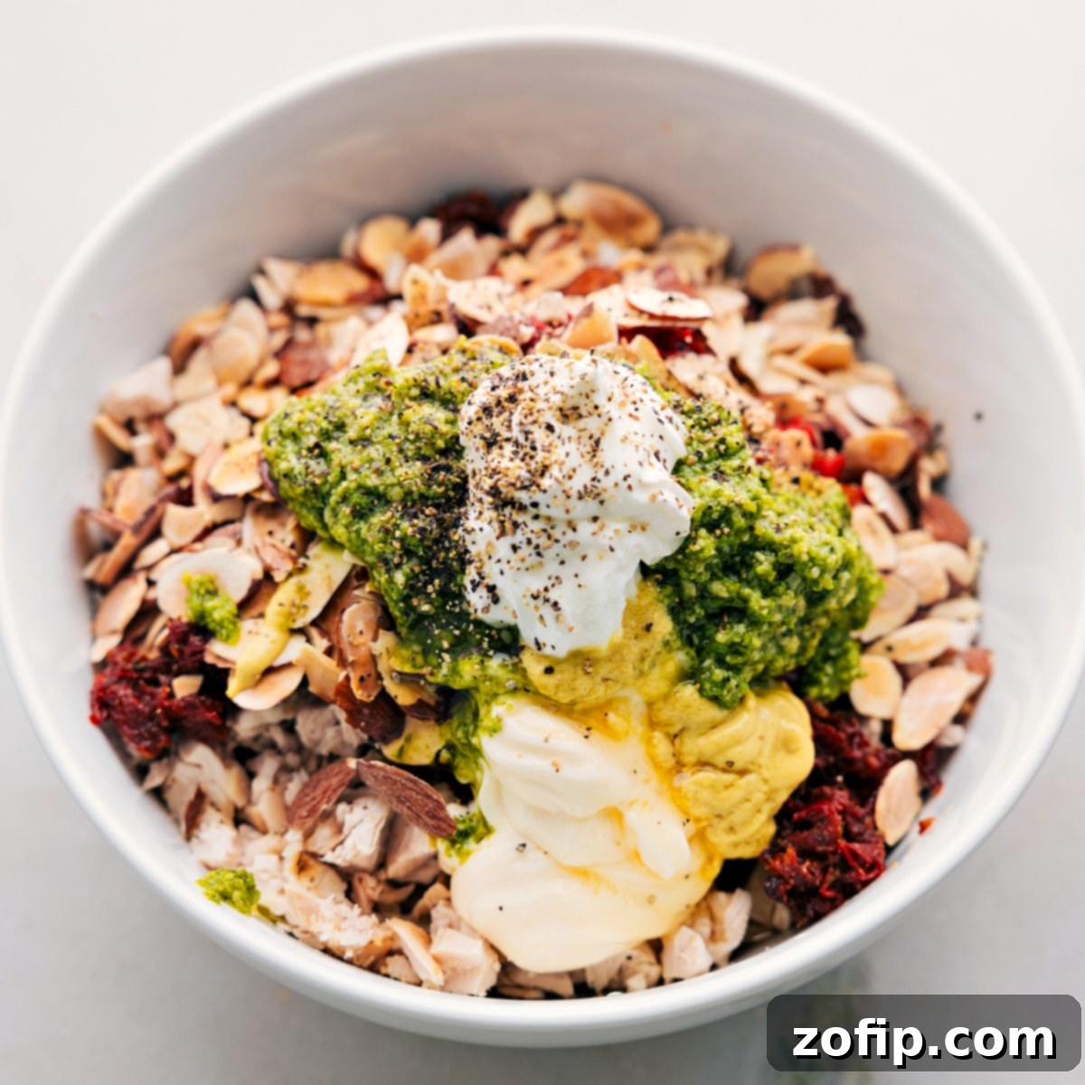 A large mixing bowl filled with all the prepped ingredients for pesto chicken salad, ready to be combined and stirred to perfection.