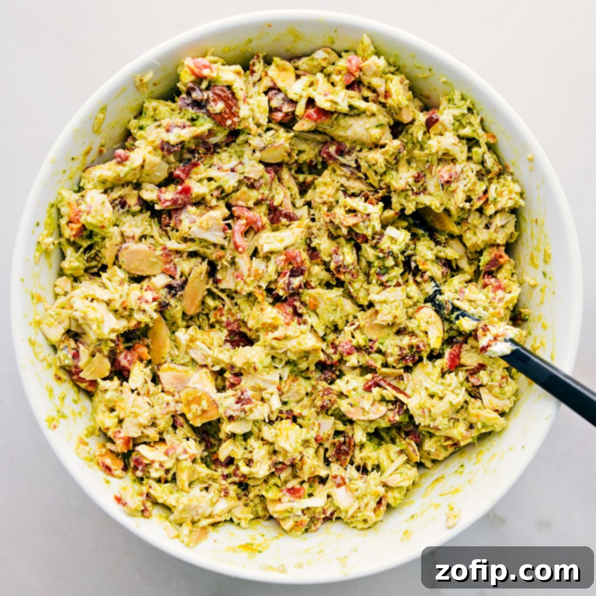 The Pesto Chicken Salad, perfectly mixed and glistening with dressing in a large bowl, ready to be served and enjoyed.