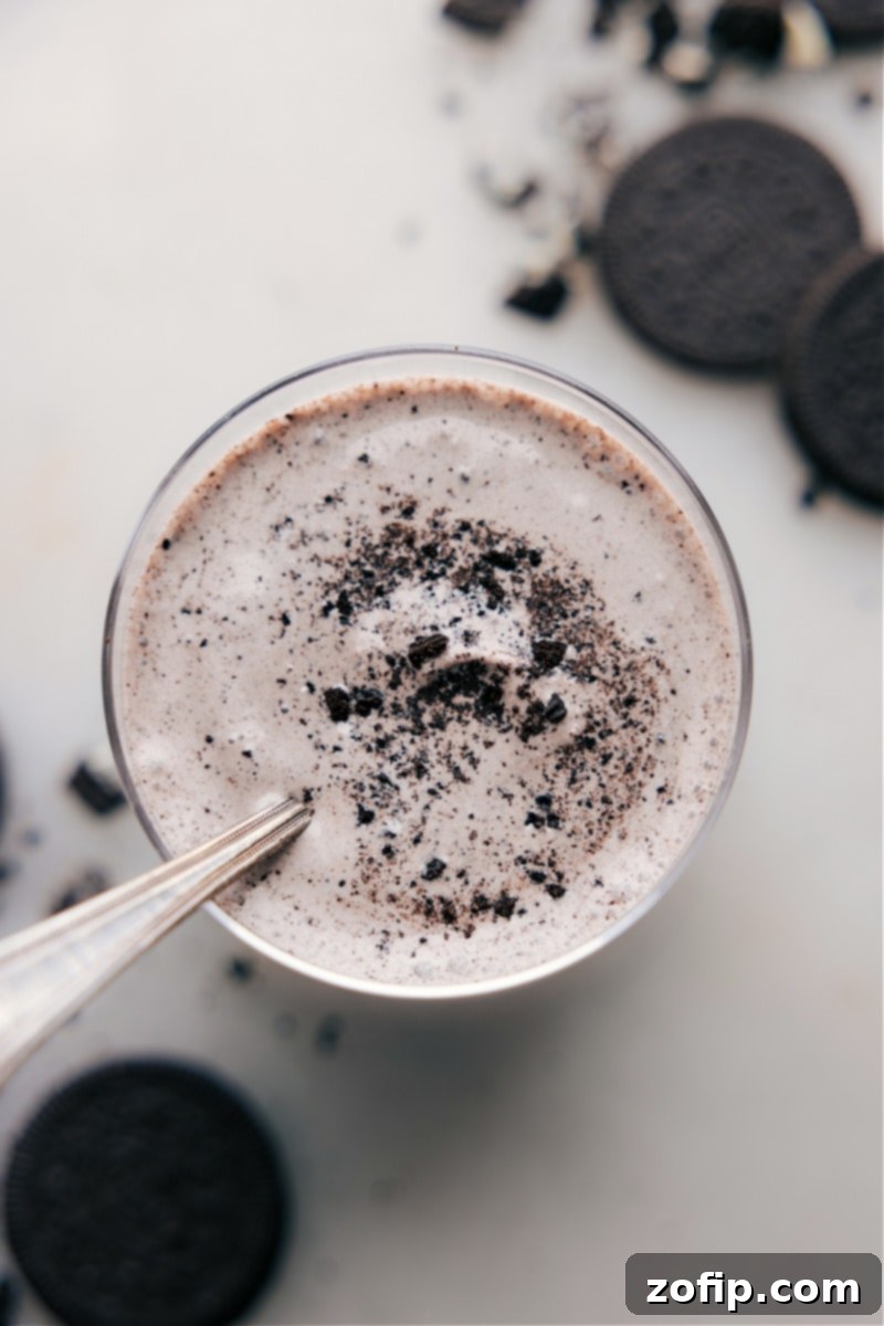 A close-up view of the delicious Oreo Milkshake, showcasing its perfect blend and toppings. An inviting overhead close-up shot of the perfectly crafted Oreo Milkshake in a glass, topped with a generous swirl of whipped cream and a sprinkle of crushed cookie pieces, highlighting its rich texture and appealing presentation.