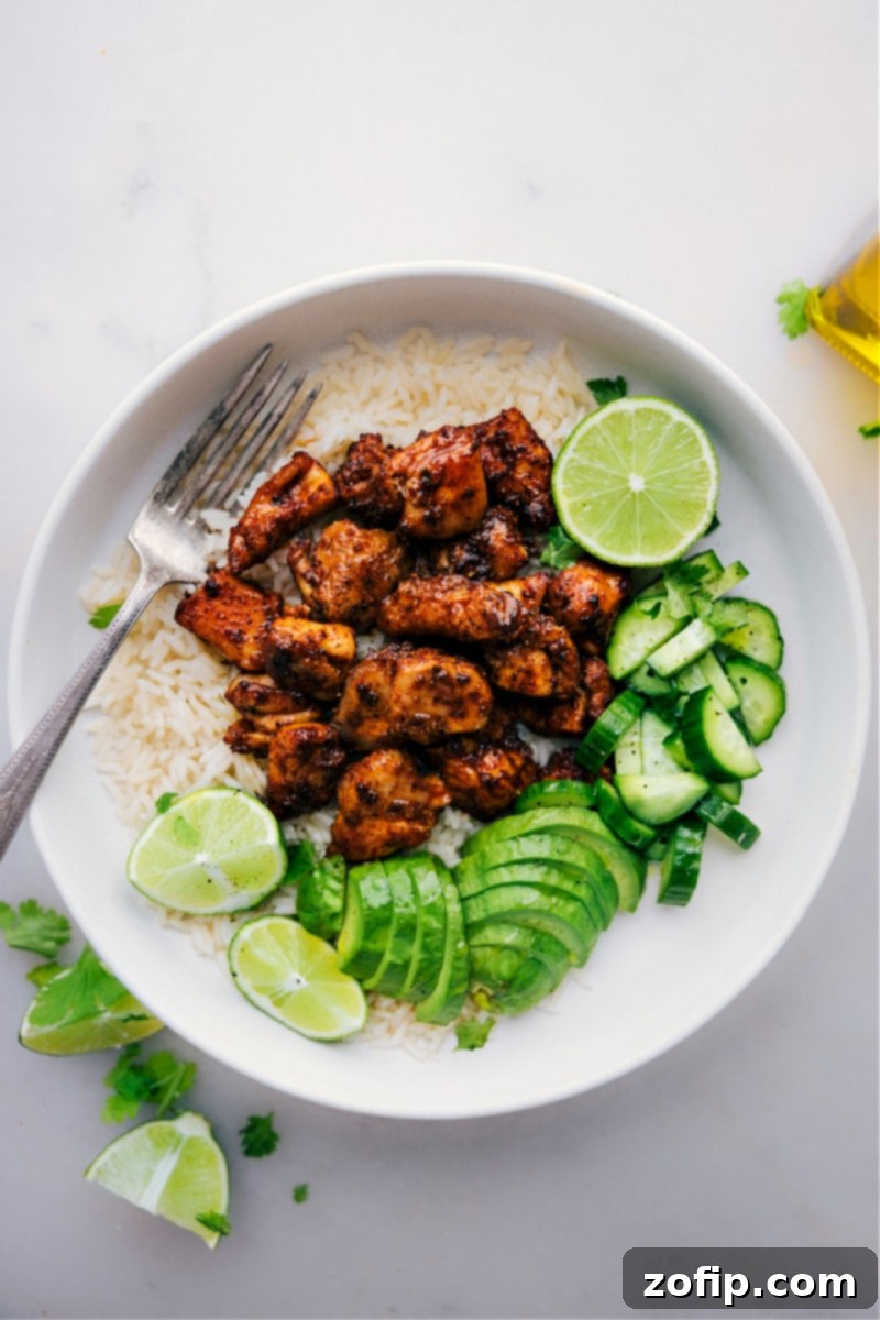 This Chipotle Chicken recipe offers an easy way to prepare bite-sized chicken pieces with a bold, smoky seasoning blend. The chicken thighs are coated in a robust seasoning blend, then broiled to achieve a caramelized exterior while keeping the interior tender. It's a versatile recipe, perfect for a quick weeknight meal or incorporated into other dishes like tacos or salads. Recipe via chelseasmessyapron #dinner #quick #easy #simple #familyfriendly #kidfriendly #onepan #healthy #chipotle #chicken Overhead image of the finished Chipotle Chicken, garnished with fresh lime and cilantro