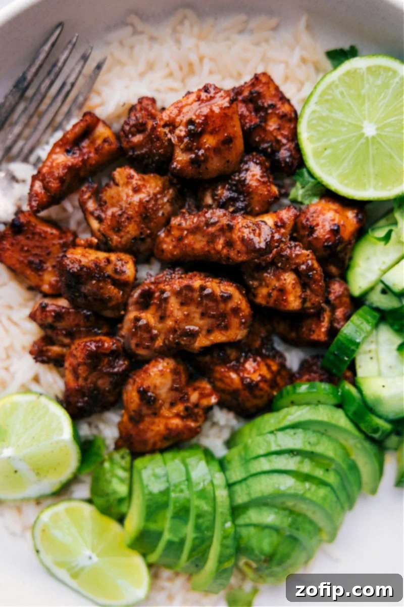 Our favorite Chipotle Chicken recipe offers an easy way to prepare bite-sized chicken pieces with a bold, smoky seasoning blend. The chicken thighs are coated in a robust seasoning blend, then broiled to achieve a caramelized exterior while keeping the interior tender. It's a versatile recipe, perfect for a quick weeknight meal or incorporated into other dishes like tacos or salads. Recipe via chelseasmessyapron #dinner #quick #easy #simple #familyfriendly #kidfriendly #onepan #healthy #chipotle #chicken Overhead image of the Chipotle Chicken dish ready to be enjoyed with fresh garnishes