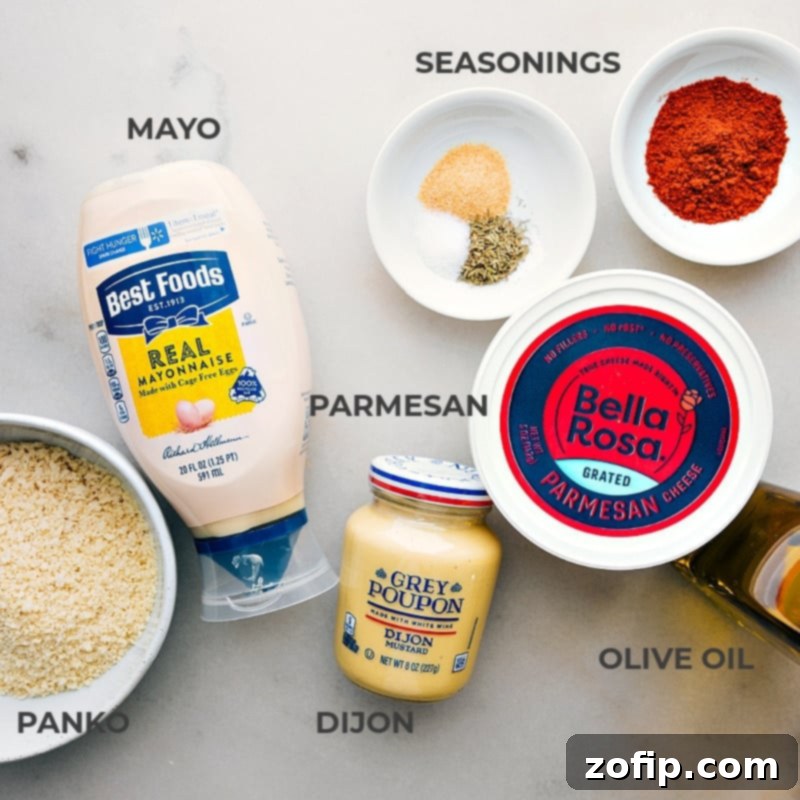 A flat lay image displaying all the fresh ingredients for the baked cod recipe: fresh cod fillets, Dijon mustard, mayonnaise, paprika, panko breadcrumbs, Parmesan cheese, olive oil, salt, pepper, thyme, garlic powder, and a lemon.