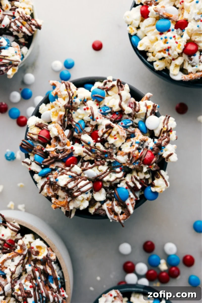 A large bowl brimming with festive 4th of July Popcorn, featuring red, white, and blue candy, crunchy pretzels, and white chocolate coated popcorn, ready to be enjoyed.
