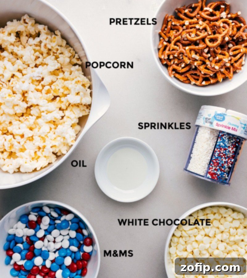 All the necessary ingredients for crafting 4th of July Popcorn are neatly arranged on a surface, including freshly popped popcorn, mini pretzels, red, white, and blue M&M's, white chocolate chips, and patriotic sprinkles, illustrating the simple components required for this festive snack.