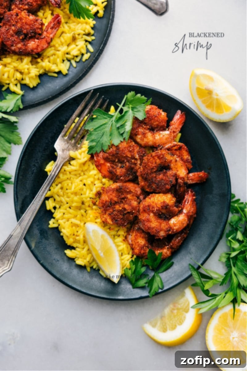Overhead image of Blackened Shrimp served with yellow rice, a vibrant veggie salad, and avocado slices.