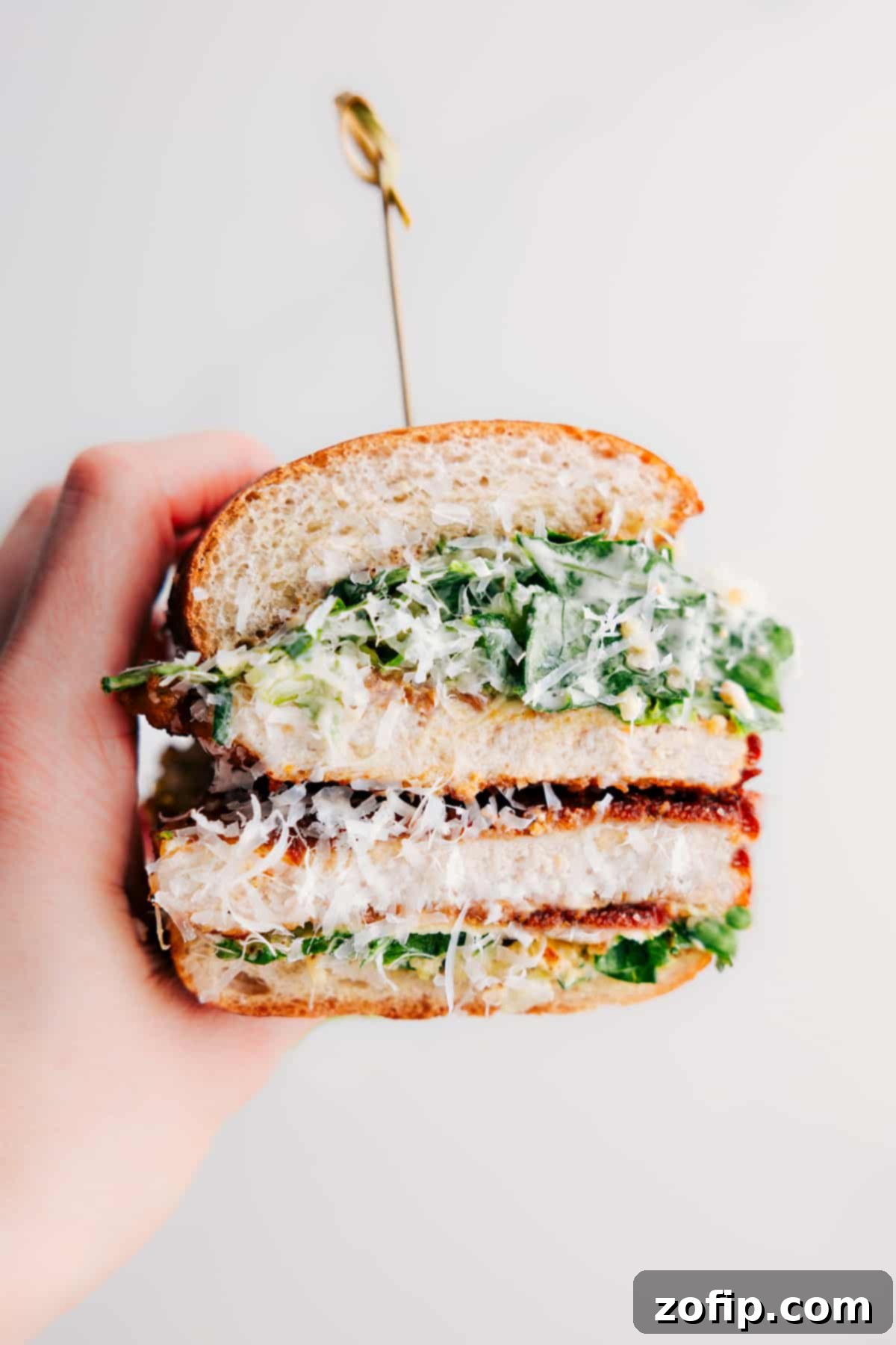 Close-up of a delicious Chicken Caesar Sandwich, revealing crispy chicken, fresh lettuce, and creamy dressing inside a toasted sub roll.