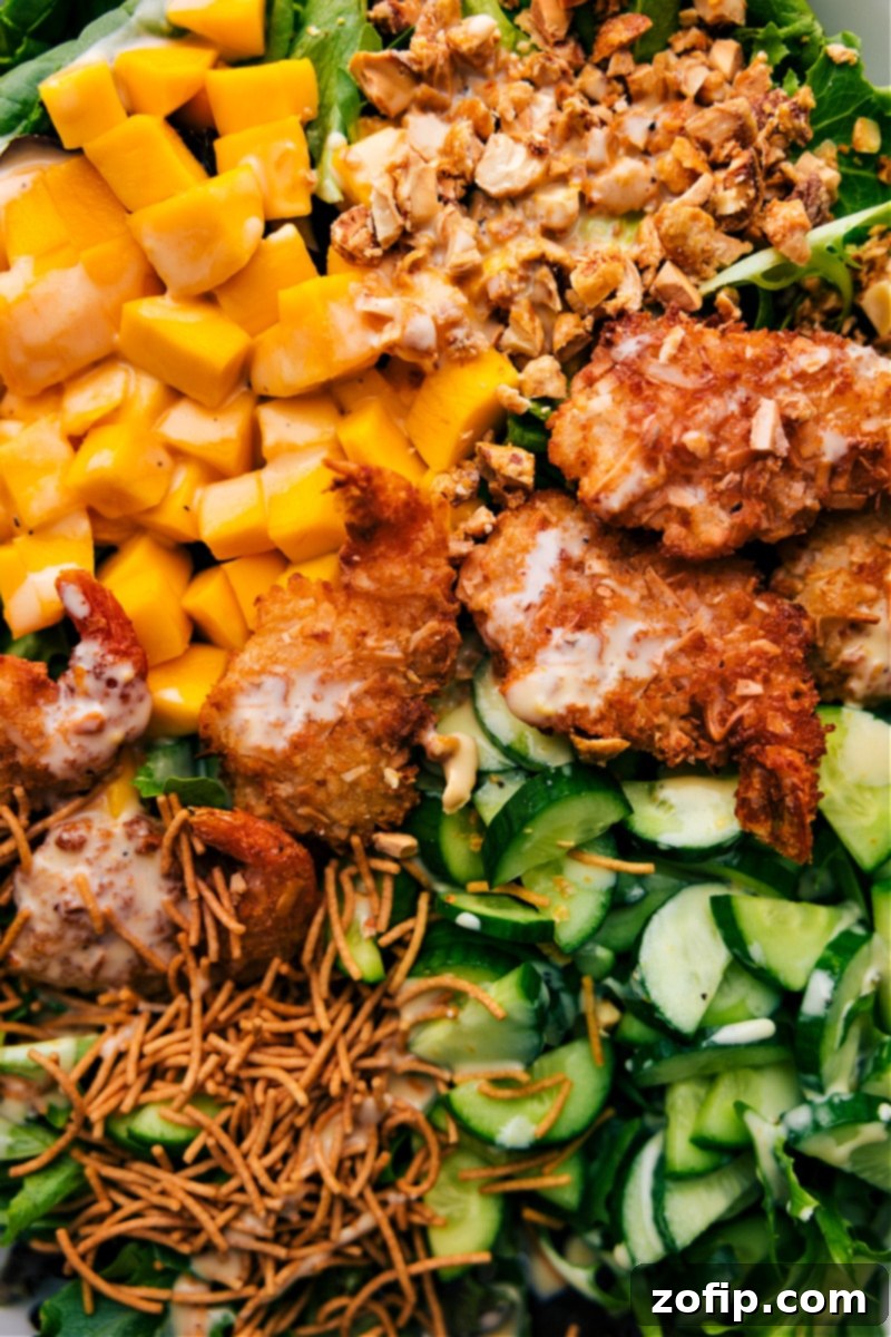 Closeup of Tropical Coconut Shrimp Salad: A vibrant and fresh meal featuring crispy shrimp and mango. A tantalizing closeup overhead view of a freshly prepared Coconut Shrimp Salad, showing the glistening dressing, crispy shrimp, bright mango, and fresh greens.