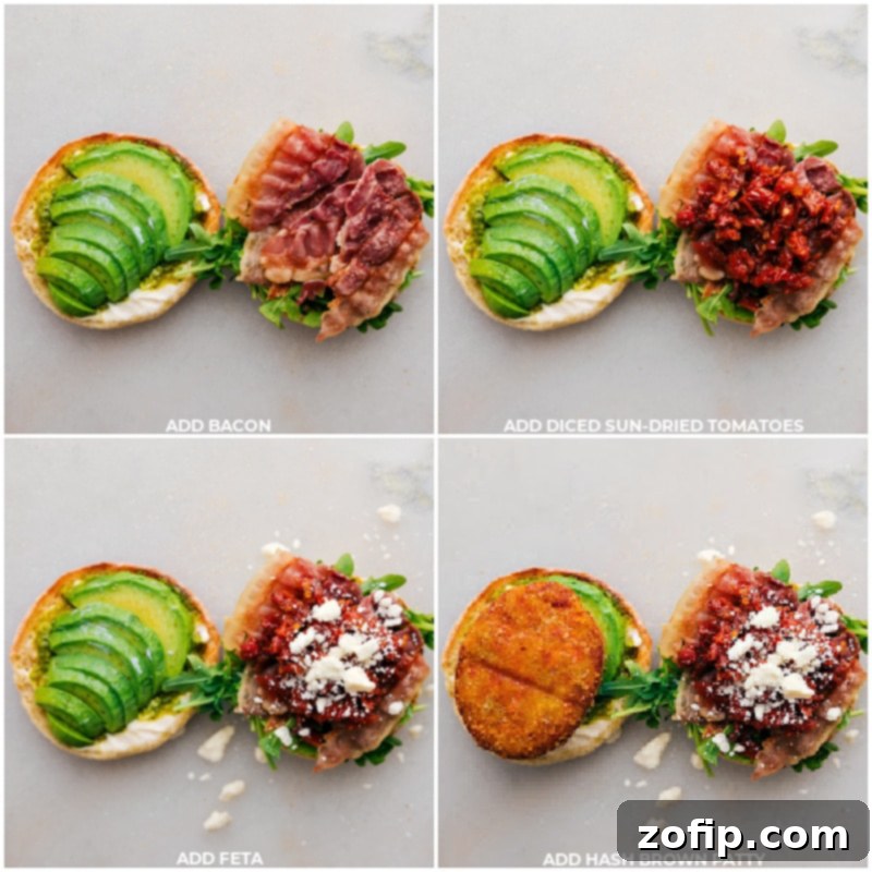 The final stages of assembling the English Muffin Sandwich, showing crispy bacon strips, finely chopped sun-dried tomatoes, crumbled feta cheese, and a golden sweet potato hash brown patty being carefully layered onto fresh greens and avocado slices