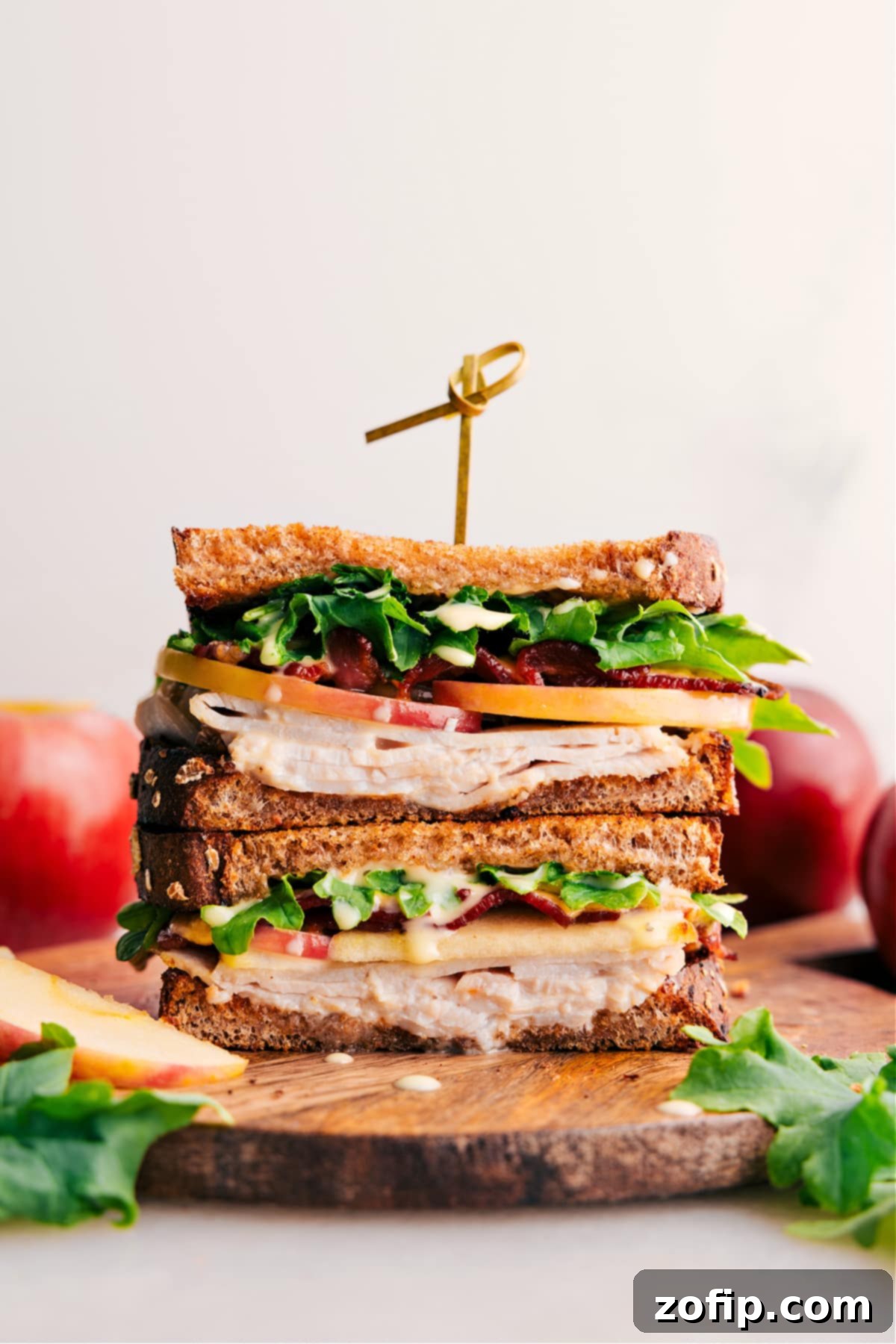 The best gourmet turkey sandwich, beautifully cut in half and stacked, showcasing its rich layers of turkey, apple, bacon, and melted Gouda, ready to be enjoyed.