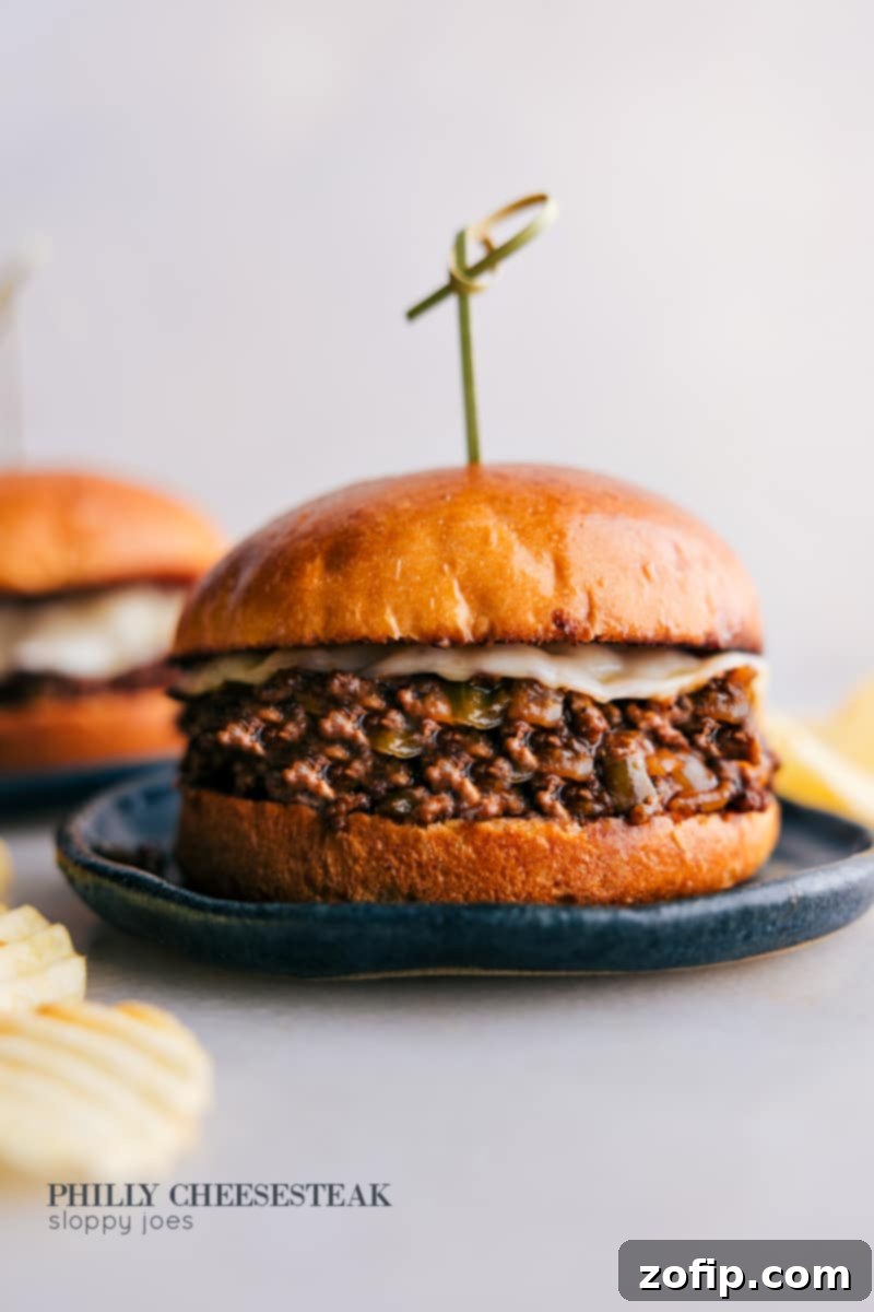 Delicious Philly Cheesesteak Sloppy Joes piled high on a brioche bun with melted cheese, served on a plate.