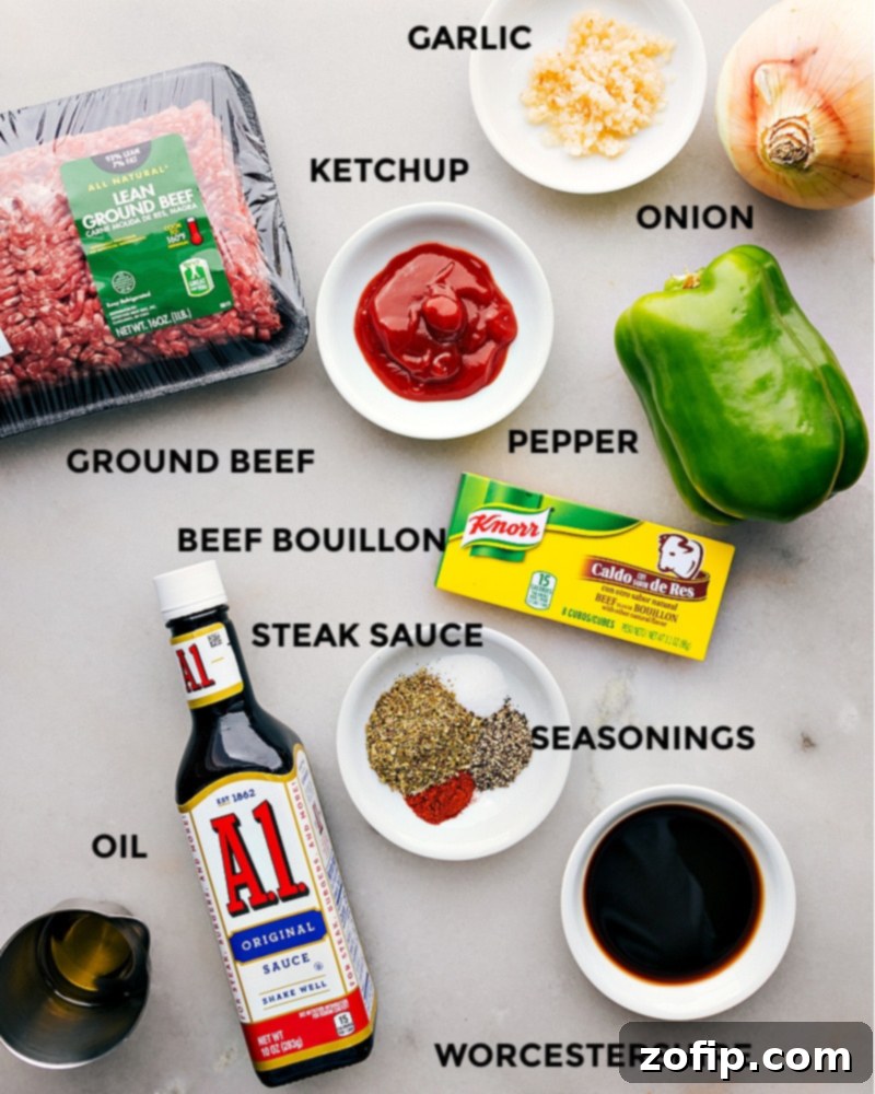 An array of fresh ingredients including olive oil, yellow onion, green bell pepper, ground beef, Italian seasoning, paprika, minced garlic, steak sauce, ketchup, Worcestershire sauce, beef bouillon powder, provolone cheese, and brioche buns, laid out for Philly Cheesesteak Sloppy Joes preparation.