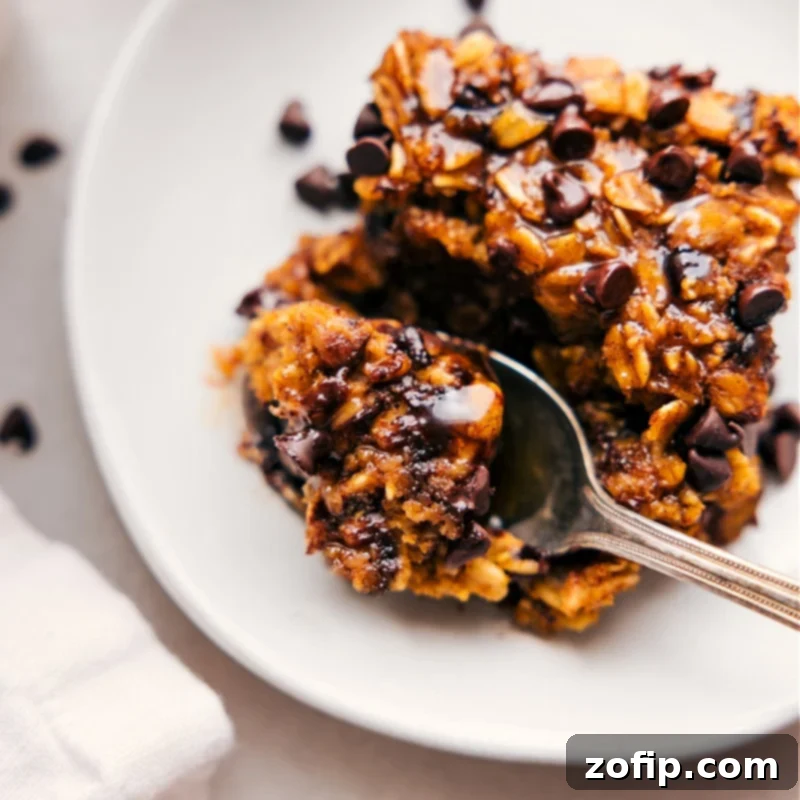 Close-up overhead image of a slice of Pumpkin Baked Oatmeal with a bite taken out, revealing its moist, perfectly spiced interior and melted chocolate chips.