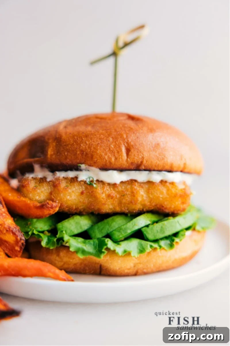 A delicious homemade crispy fish sandwich with avocado and lemon dill sauce on a brioche bun, ready to eat.