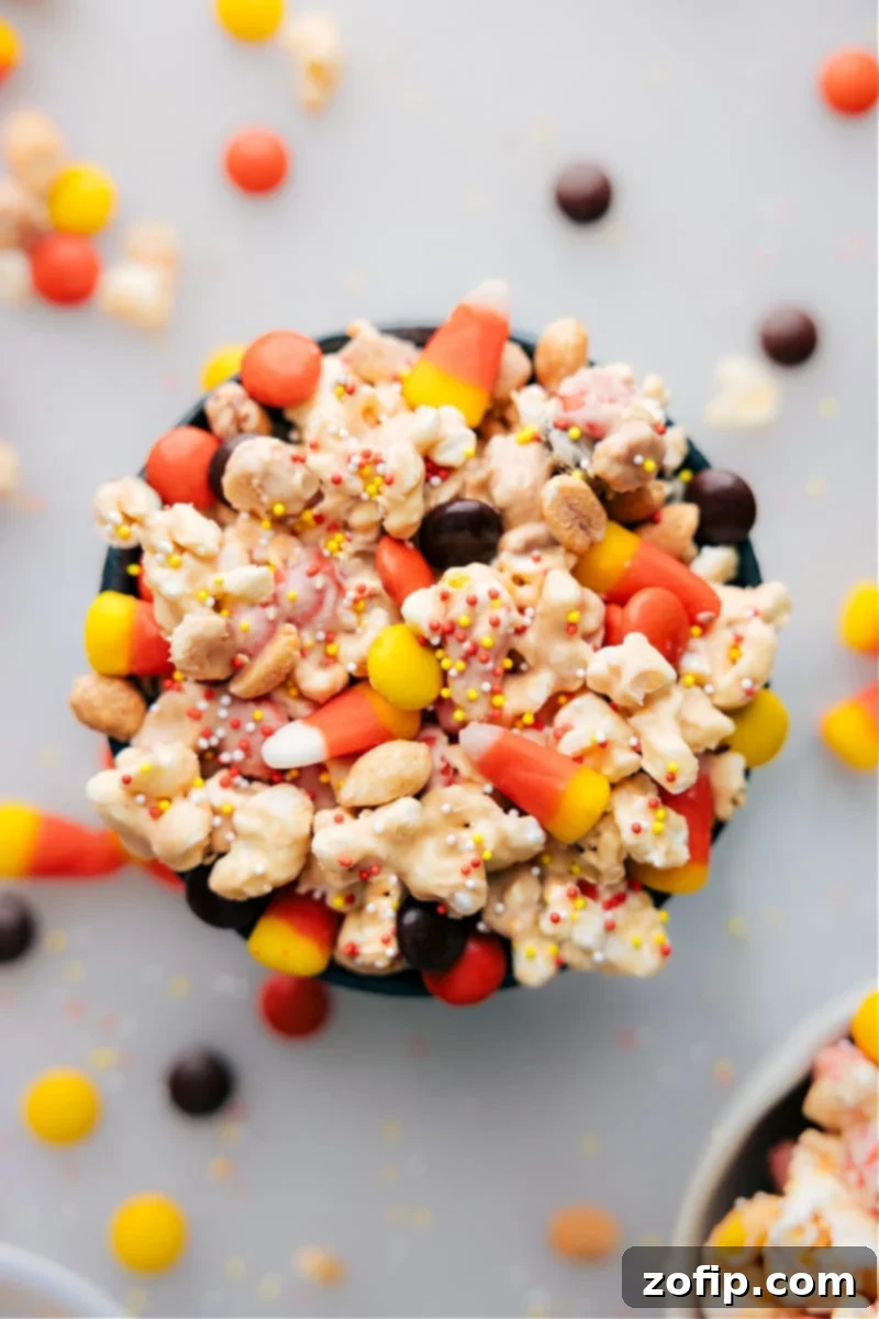 Overhead view of a large bowl filled with vibrant Candy Corn Popcorn, showcasing the mixture of white chocolate, peanut butter, candy corn, and peanuts.