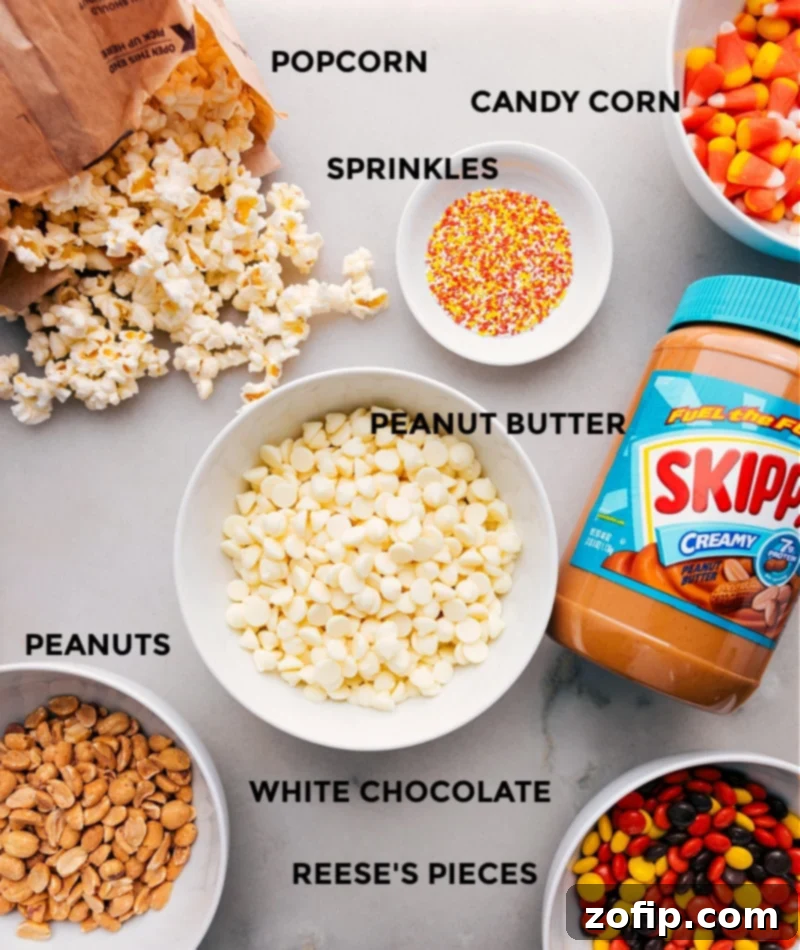 Collection of ingredients needed for Candy Corn Popcorn, including popcorn, candy corn, Reese's Pieces, peanuts, white chocolate chips, peanut butter, and salt.
