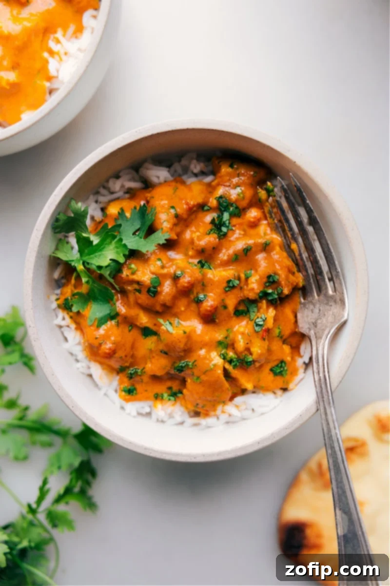 A vibrant bowl of creamy Instant Pot Butter Chicken served over steamy white rice, elegantly garnished with fresh green cilantro leaves, ready to be enjoyed.
