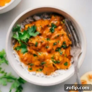 Bowl of creamy instant pot butter chicken served over rice, garnished with fresh cilantro.