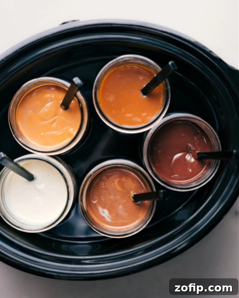 Overhead view of several mason jars filled with warm dipping sauces, nestled in a Crock-Pot filled with water, illustrating the method for keeping dips perfectly warm for serving.