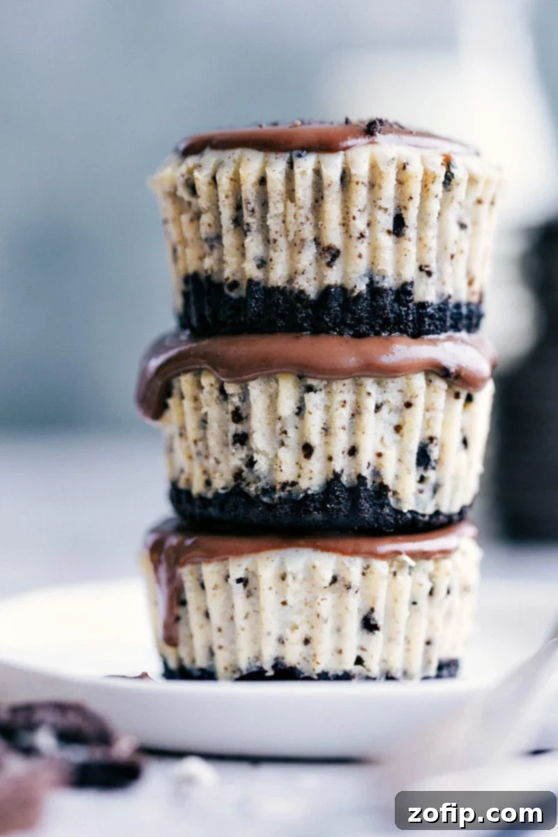 Stack of three perfectly baked Mini Oreo Cheesecakes topped with rich chocolate ganache, ready to serve.