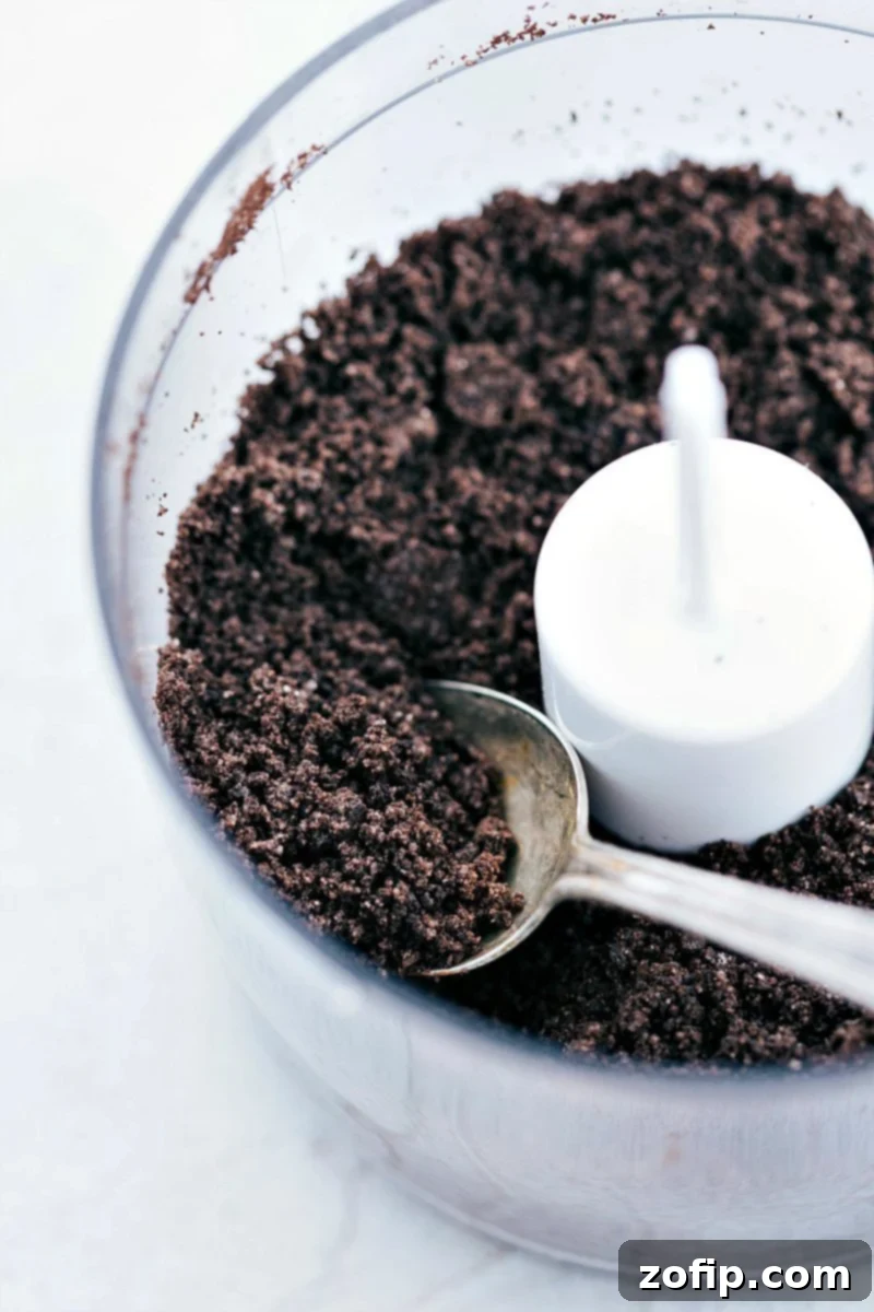 Crushed Oreo cookie crumbs in a food processor, ready to be made into a delicious cheesecake crust.