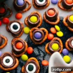 A close-up of a finished Monster Eyeball, showcasing the salty pretzel base, gooey Rolo caramel, and a vibrant M&M or edible eye topping, ready for Halloween.