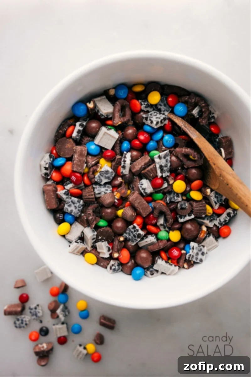 Candy Salad: The most fun mishmash of sweet and salty flavors, featuring standouts like Whoppers, Reese's, and chocolate-covered pretzels. It's the perfect treat for when you're craving a combo of the most iconic candies in one bite or looking for a surefire hit at your next gathering! Overhead image of a vibrant Candy Salad in a large serving bowl, showcasing various candies like Whoppers, Reese's, and chocolate-covered pretzels.