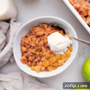 Freshly baked apple cobbler with a golden-brown, crumbly topping and tender apple filling in a baking dish.