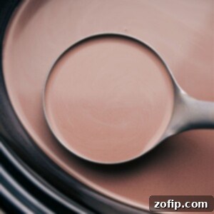 A spoonful of the warm beverage, poised and ready to be poured into a waiting mug.