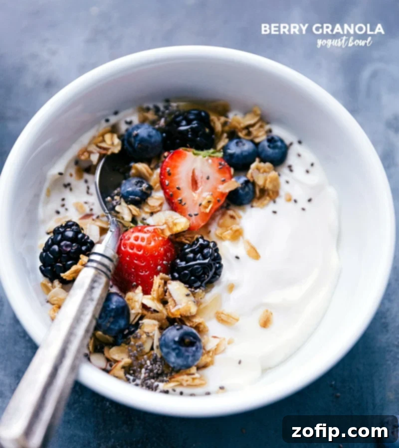 A beautifully arranged Berry-Granola Yogurt Bowl, generously topped with fresh blueberries, raspberries, and crunchy granola, served with a spoon. Perfect for a healthy and delicious breakfast.