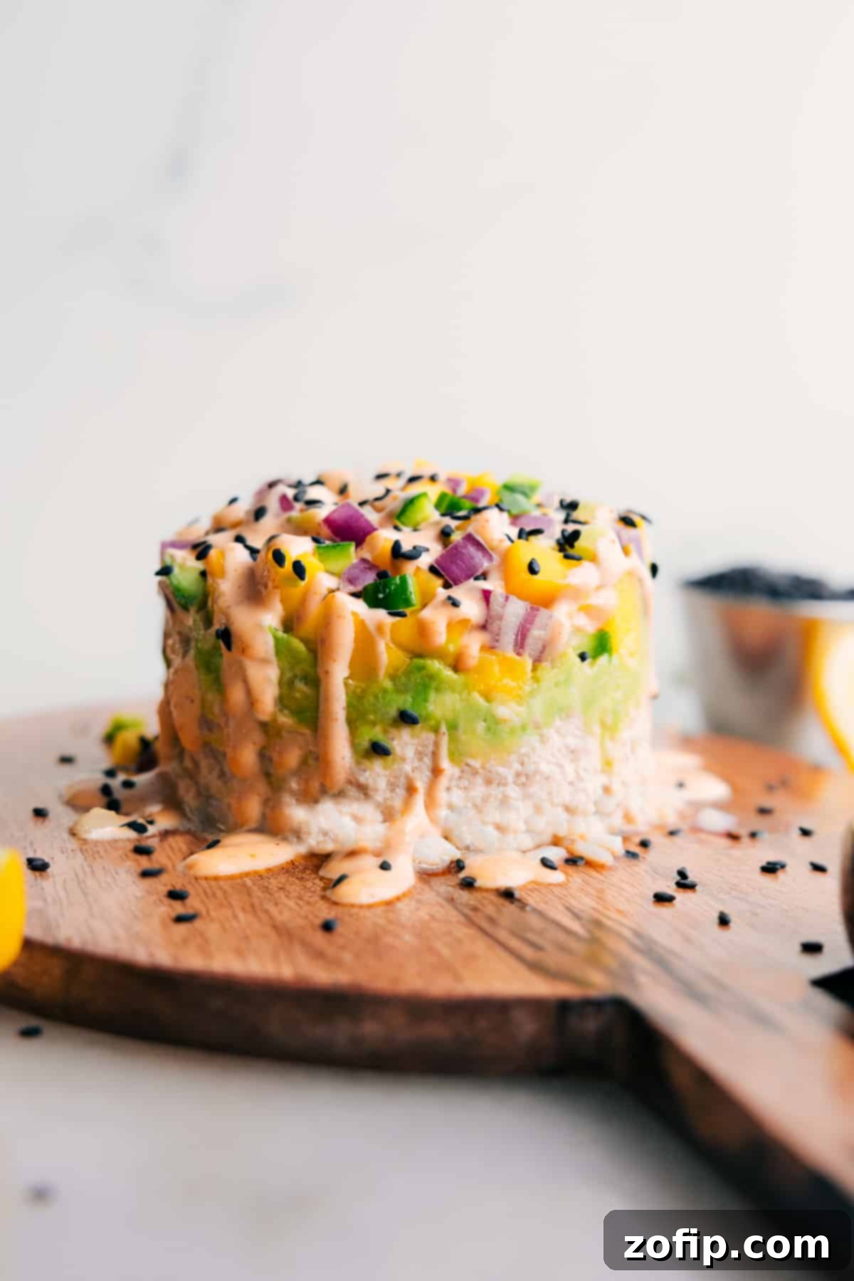 Enjoy this Tuna Stack drizzled with creamy sriracha mayo, showcasing vibrant layers of tuna, avocado, mango, and rice.